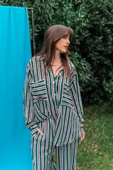 Camisa de fibrana con diseño de rayas verticales en tonos verde, blanco y violeta, de manga larga, cuello camisero, cierre frontal con botones y bolsillos plaqué en el pecho.