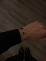 Pulsera de acero con cadena de eslabones y cinco dijes en forma de trébol con incrustaciones de nácar blanco.