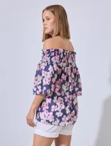 Blusa de gasa estampada con flores rosas y verdes sobre fondo azul marino. Escote bote con punto smock y mangas cortas amplias.