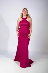 Vestido largo de fiesta color fucsia, con escote halter y corte sirena que se ajusta al cuerpo hasta la rodilla y se ensancha hacia el ruedo.
