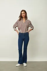Jean de denim azul de corte flare, con tiro medio, diseño de botamanga acampanada y sutil estampado texturizado en toda la prenda.
