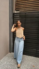 Top halter color beige, estilo chaleco corto, con cuello alto y bordes festoneados con costura decorativa.