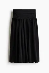 Pollera midi de punto color negro con diseño de bajo globo que crea una silueta abullonada. Cuenta con una cintura ancha elastizada y frunces.