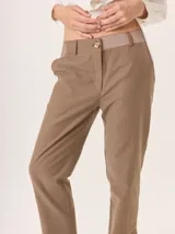 Pantalón de vestir azul marino, corte cigarette con pierna angosta y abertura en el bajo. Presenta costuras en contraste color beige y un botón marrón en la cintura.