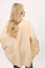 Camisa oversize a rayas verticales rosas y blancas, con cuello clásico, cierre frontal con botones y mangas largas.