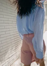 Camisa de manga larga con diseño a rayas en tonos celestes y blancos, cuello camisero y cierre frontal con botones.