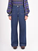 Jean de tiro alto con corte recto y amplio, confeccionado en denim azul oscuro. Presenta dos bolsillos frontales tipo parche y cierre con botón metálico.