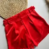 Short rojo de satén con bolsillos delanteros, pasacintos y cinturón de la misma tela.