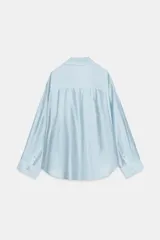 Camisa amplia de cuello solapa con escote en pico y manga larga, en tejido satinado de color bordó. Cuenta con un bolsillo de plastrón en el frente y un diseño holgado.