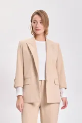Blazer de color visón con mangas tres cuartos, solapas clásicas y cierre frontal con un botón. Presenta bolsillos laterales con solapa.