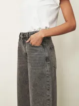 Jean de corte wide leg en color gris con efecto lavado. Presenta tiro medio, cierre frontal con botón y bolsillos laterales y traseros.