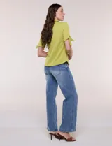 Camisa blanca de manga corta con cuello solapa, cierre frontal de botones, detalles bordados al tono en el pecho y lazos para anudar en las mangas.