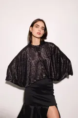 Camisa negra con estampado de hojas en relieve, cuello camisero, mangas anchas y corte cropped.