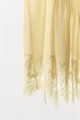 Top de tirantes finos con escote en pico, confeccionado en tejido georgette semitransparente. Presenta un diseño con pliegues verticales en el frente y un delicado bajo acabado en encaje a tono.