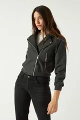 Campera corta negra con corte entallado, cierre frontal asimétrico y bolsillos con cremallera.