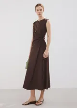 Vestido midi cruzado de color marrón, confeccionado en mezcla de lino y algodón, con cuello redondo, sin mangas y lazo ajustable en la cintura.