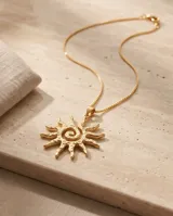 Collar de bronce con baño de oro, compuesto por una cadena fina y un dije colgante en forma de sol con textura irregular y detalles de circonitas incrustadas.