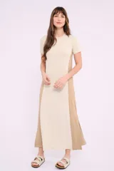 Vestido midi de corte recto y diseño bicolor, con frente en color crema y laterales en color beige. Presenta cuello redondo, mangas cortas y aberturas laterales en el ruedo.