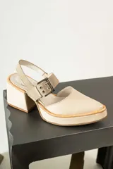 Zapato de tacón cuadrado y plataforma, color beige, con punta cerrada y tira ajustable con hebilla metálica en el tobillo.