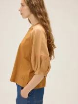 Remera de algodón con escote a la base y mangas raglán de broderie con costuras decorativas en color contrastante.