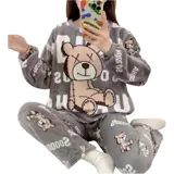 Conjunto de pijama de dos piezas confeccionado en tela de plush suave y abrigada. Incluye una remera de manga larga con diseño estampado de Totoro y pantalón largo a juego con puños en contraste.