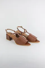 Sandalias de cuero rojo con diseño de tiras horizontales abullonadas en la parte delantera, punta fina, tira vertical central en forma de T y tira ajustable al tobillo. Poseen tacón cuadrado de madera de 6 cm.