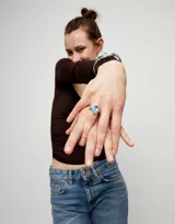 Anillo de aleación de metales con baño de plata de ley, presenta un cristal facetado de color azul en talla ovalada engastado en el centro.