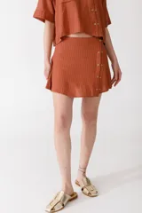 Minifalda color ladrillo con rayas verticales finas y botones dorados en el lateral.