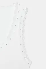 Musculosa de algodón color negro, con escote redondo y tiras anchas. Presenta detalles de encaje negro en los bordes y aplicación de perlas pequeñas alrededor del escote y los hombros.