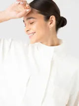 Buzo estilo polerón color blanco off-white, confeccionado en tela suave y ligera. Presenta cuello alto, cierre frontal con tapeta de botones a presión, bolsillos frontales con solapa y pretina elástica en la cintura.