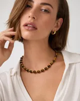 Collar corto compuesto por cuentas esféricas de piedra natural ojo de tigre alternadas con pequeñas cuentas metálicas doradas.