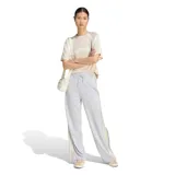Pantalón deportivo Adidas modelo W Sta Seas Pt para mujer, de tejido de malla color gris con tiras laterales a rayas y botones a presión. Cuenta con cintura elástica con cordón de ajuste y logo de la marca bordado.