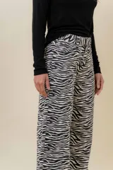 Jean de tiro medio a alto con estampa de cebra en blanco y negro, de corte wide leg. Posee bolsillos funcionales delanteros y traseros, y cierre frontal con botón.