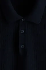 Remera polo de manga corta en punto texturizado negro, con cuello y tapeta de tres botones. Remate acanalado en puños y bajo, con un corte estándar.