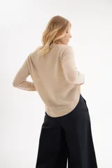 Sweater de punto color beige claro, con cuello redondo y mangas largas. Presenta un tejido acanalado horizontal en el cuerpo y acanalado vertical en las mangas.