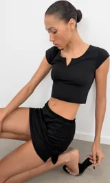 Falda corta gris melange de tiro medio con cintura elástica, confeccionada en hilatura con mezcla de algodón. Cuenta con forro interior tipo shorts del mismo tejido.