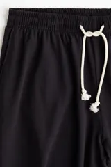Pantalón de jogging negro de corte amplio, con cintura elástica ajustable con cordón y bolsillos laterales.