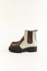 Botas cortas de cuero color marrón y beige, con elástico lateral y suela track color negro.