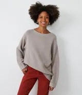 Suéter largo de punto texturizado color gris topo, con cuello redondo y mangas largas.