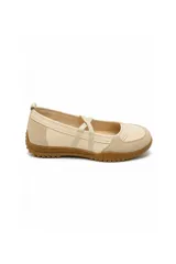 Zapatilla tipo chatita o ballerina color beige, con tiras cruzadas elásticas sobre el empeine, detalles en gamuza y suela de goma marrón con textura.