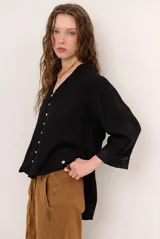 Camisa de lino color blanco, con escote en V, mangas tres cuartos con detalles de encaje en los puños y ruedo asimétrico más largo en la parte trasera.