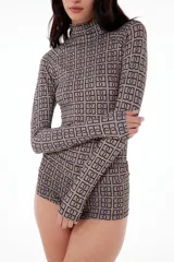 Polera de cuello alto y manga larga, confeccionada en tela elastizada con estampado de figuras geométricas en tonos beige y negro.