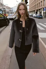 Chaqueta de cuello redondo y manga larga con tejido exterior efecto pelo e interior efecto ante. Presenta bolsillos delanteros de vivo y cierre frontal con alamares metálicos.