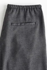 Pantalón de corte holgado y piernas rectas, confeccionado en tejido con textura de espiguilla. Presenta cintura elástica con cordón de ajuste, bolsillos laterales y bolsillos traseros decorativos.