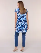 Túnica de gasa negra con estampado floral en tonos azules y blancos, cuello camisero, manga corta y cierre frontal de botones.