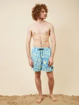 Short de baño celeste con estampado de soles y texto en amarillo.