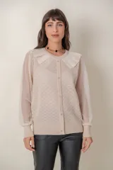 Cárdigan color beige con botones de strass, cuello de tul y mangas de plumeti.