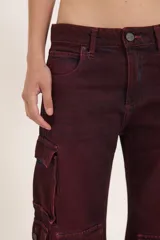 Pantalón jean cargo color borgoña, de pierna ancha y tiro medio, con múltiples bolsillos con solapa y broches.