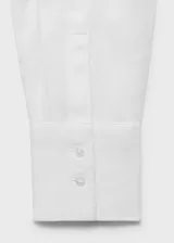 Camisa blanca oversize de lino, con cuello camisero, manga larga con puños abotonados y cierre frontal con botones.