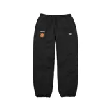 Pantalón deportivo de corte holgado en color negro, colaboración entre Supreme y Umbro. Presenta cintura y puños elásticos, con el logo de Supreme y un escudo circular en la pierna derecha y el logo de Umbro en la pierna izquierda.